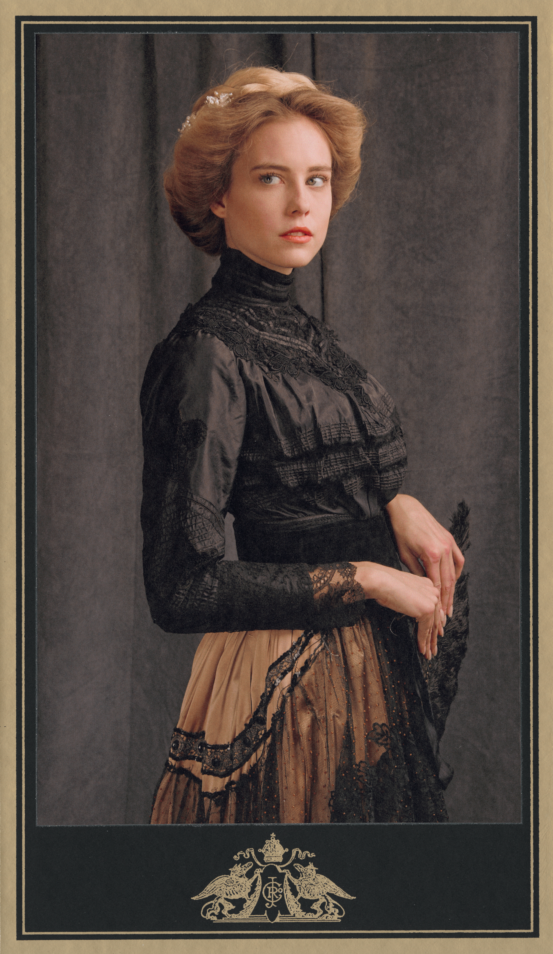 1890s fashion inspired advertising photo shoot by fashion stylist katalina sasdy. a blonde lady in a black, 1900s style silk and lace blouse and a pink silk skirt with black lace, including a black belt, is holding a black strauss feather fan in her hands and is looking flirty into the camera. her hairstyle is pinned up in the style of the belle epoque and held together with a silver hair clip with pearls.