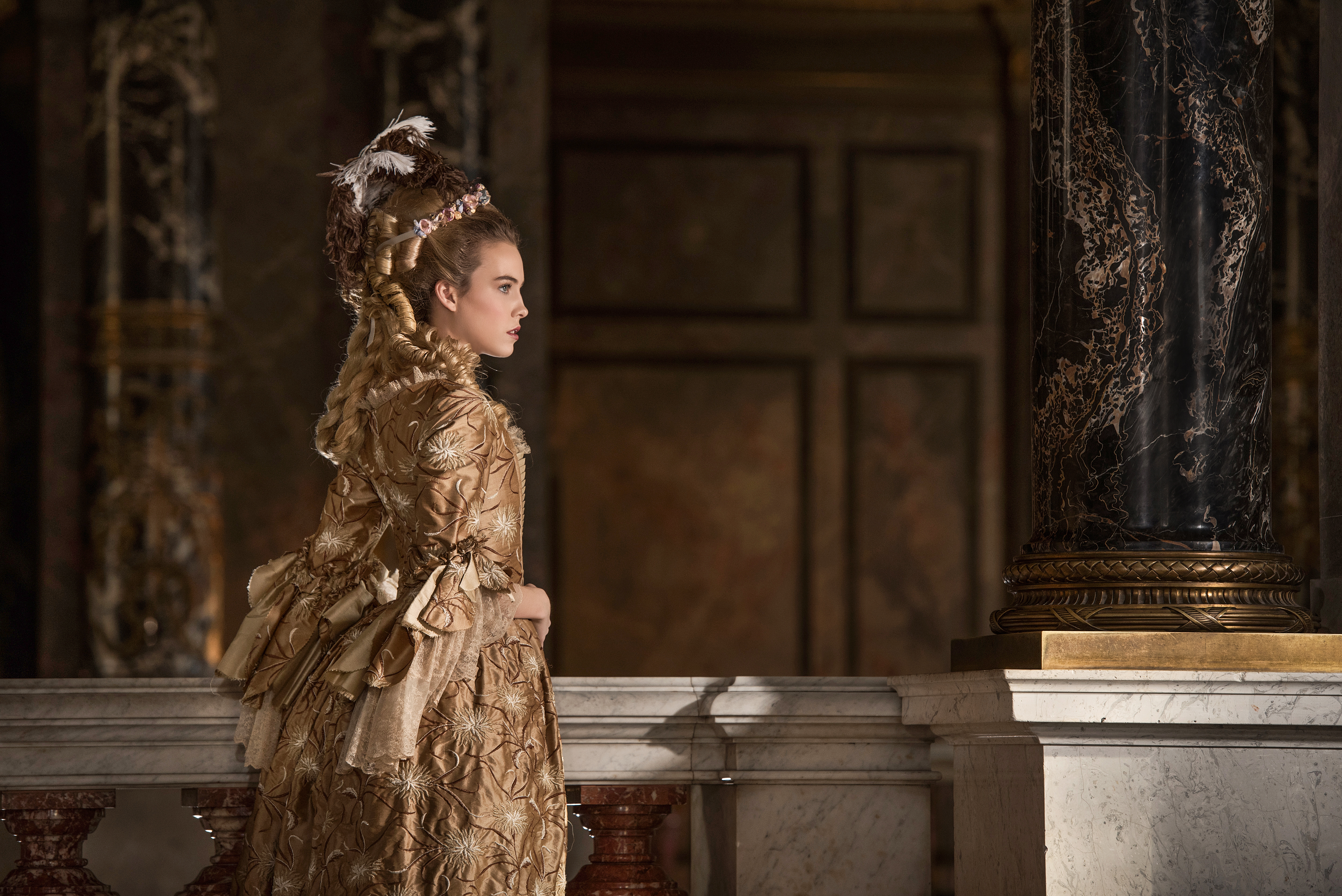 georgian fashion inspired advertising photo shoot in khm vienna by fashion historian and stylist katalina sasdy. marie antoinette is standing in profile on the terrace in a yellow silk rococo dress. her hair is in the fashion of pouf hairstyles of the 18th century.